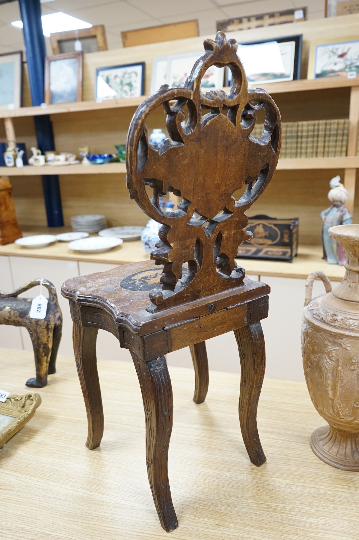 A 19th century Black Forest carved child’s musical chair with integral music box, the seat and back each inlaid with an animal cartouche, 68cm high